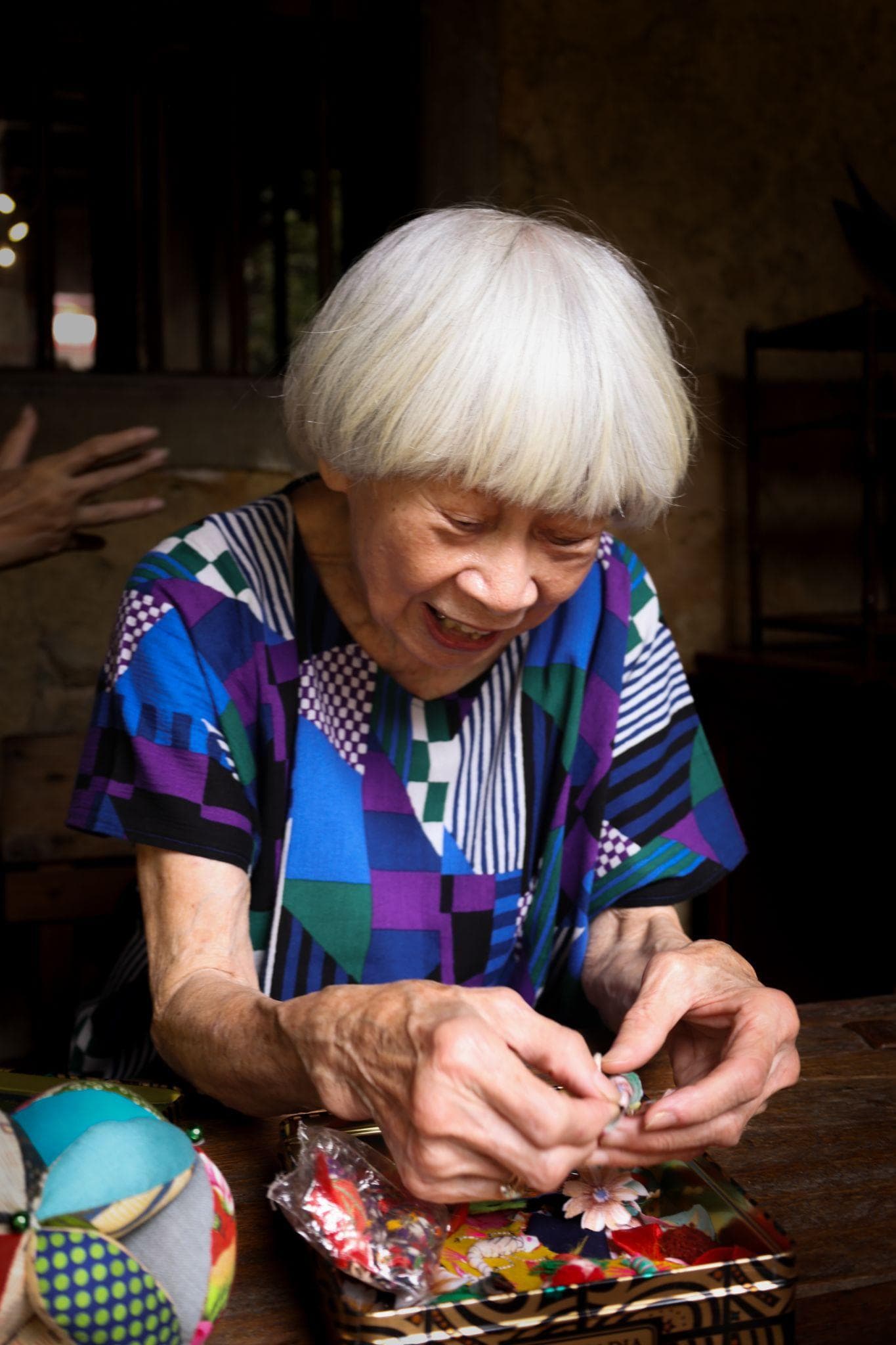 Gu MaMa handcrafting a small ornament inside her community home