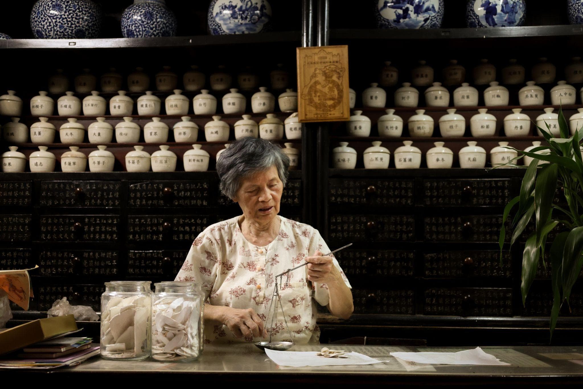 Huang Hui-Me weighing herbs inside her Chinese medicine pharmacy